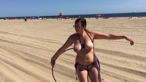 Una ragazza di spiaggia hot mostra le sue abilità con l'hula hoop.